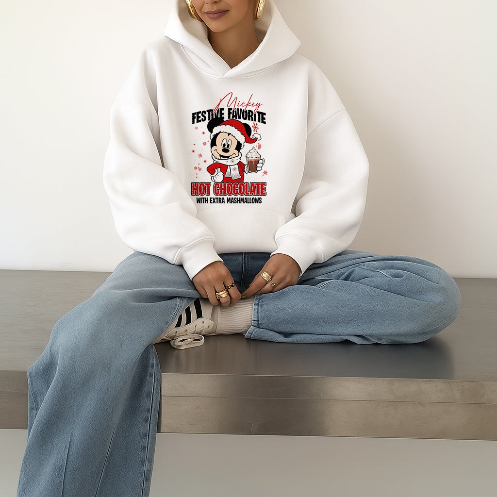 Woman wearing a white hoodie with a festive Mickey Mouse design, sitting on a bench.