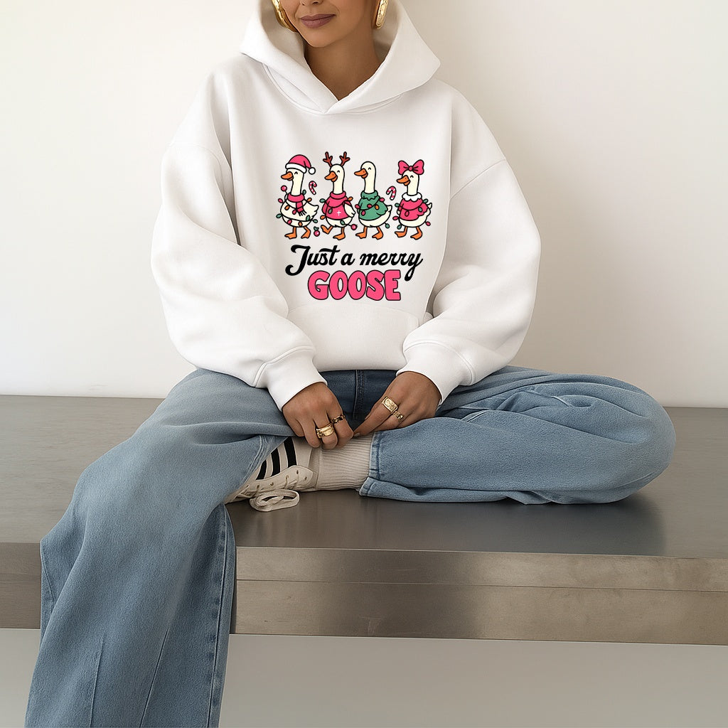 Woman wearing a white hoodie with a Christmas-themed goose graphic design and text, sitting on a bench.