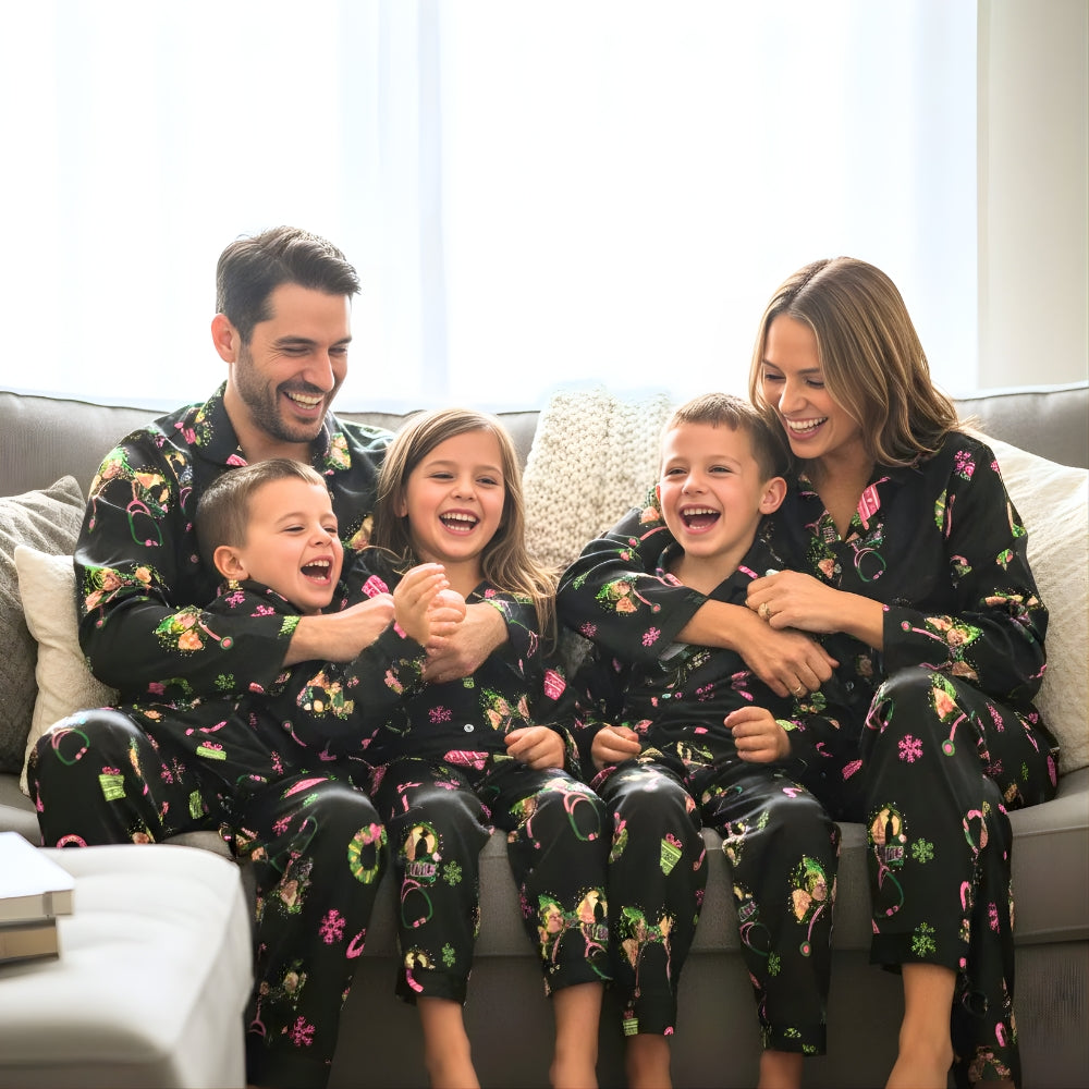 Family of five wearing matching black Christmas-themed pajama set with Wicked designs sitting on a couch.