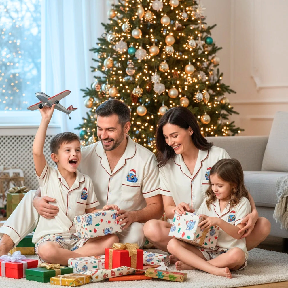 Family of four in matching pajamas with colorful Derpy tiger patterns and holiday designs sitting on the floor in front of a Christmas tree with presents.