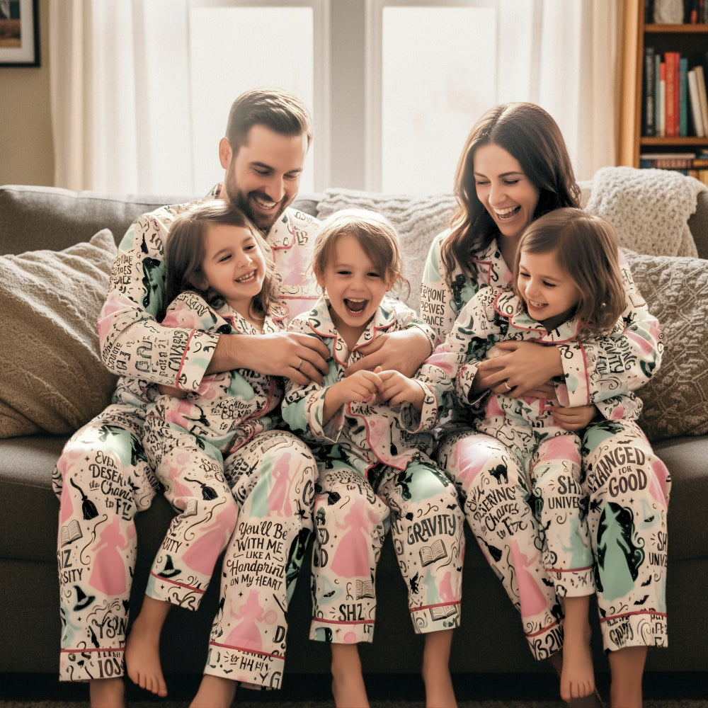 Family of four wearing matching pajamas with the enchanting world of Oz design with a stylish, theatre-inspired twist sitting on a couch in a cozy living room.