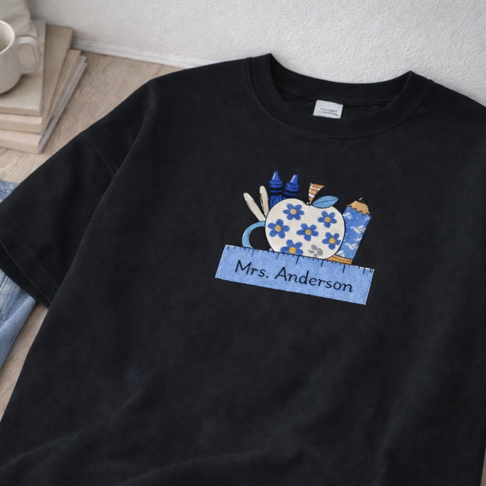 Black t-shirt with a colorful design and 'Mrs. Anderson' text on a wooden surface.